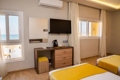 a hotel room with two beds and a flat screen tv at Al Dora Residence Suites Hurghada in Hurghada
