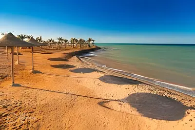 a sandy beach with a group of umbrellas and the ocean at Al Dora Residence Suites Hurghada in Hurghada