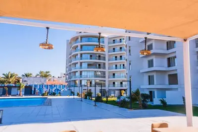 a large white apartment building with a swimming pool at Scandic Resort - Mido Chalet in Hurghada
