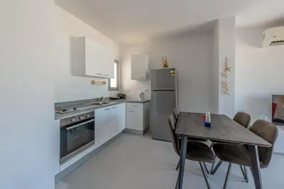 a kitchen with a table and chairs and a refrigerator at New! Lovely 1BR in Swan Lake, Gouna. Azure Lagoon in Hurghada