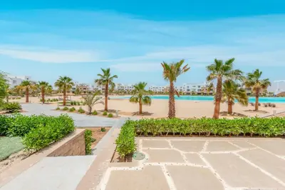a view of the beach and palm trees at the resort at New! Lovely 1BR in Swan Lake, Gouna. Azure Lagoon in Hurghada