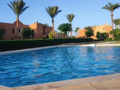 a swimming pool with palm trees in the background at Chalet Stella Makadi Beach 5* in Hurghada