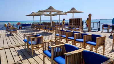 a deck with chairs and umbrellas on the beach at Chalet Stella Makadi Beach 5* in Hurghada