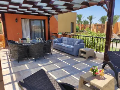 a patio with a blue couch and a table and chairs at Chalet Stella Makadi Beach 5* in Hurghada