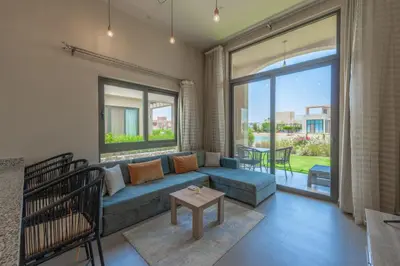 a living room with a blue couch and a large window at NEW! 2BR Duplex in Tawila, Gouna Private Jacuzzi, Garden, Lagoon & Pool in Hurghada