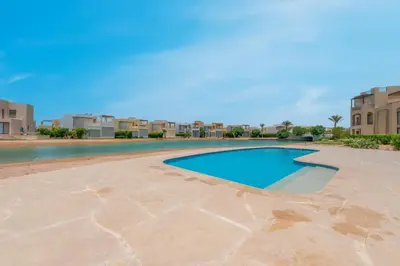 a swimming pool in a resort with buildings in the background at NEW! 2BR Duplex in Tawila, Gouna Private Jacuzzi, Garden, Lagoon & Pool in Hurghada