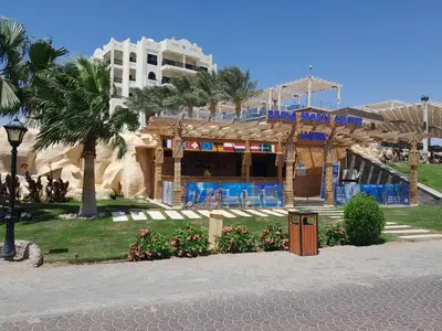 a building on the beach with a hotel in the background at Sea View at Gravity Sahl Hasheesh 7 Pools & Beach-FOR GUESTS WITH NONEGYPTIAN PASSPORTS in Hurghada