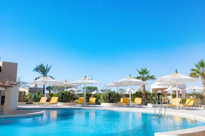 a swimming pool with chairs and umbrellas at Lemon & Soul Makadi Garden in Hurghada