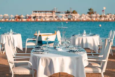 a group of tables and chairs with white table cloths on the beach at Lemon & Soul Makadi Garden in Hurghada