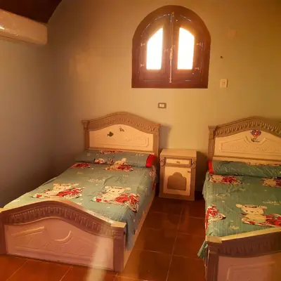 a bedroom with two twin beds and a window at Malika nubian house in Aswan
