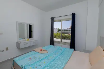 a white bedroom with a bed and a window at La bonita one bedroom apartment in Hurghada