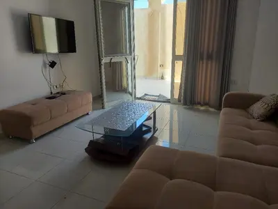 a living room with a couch and a tv at La bonita one bedroom apartment in Hurghada