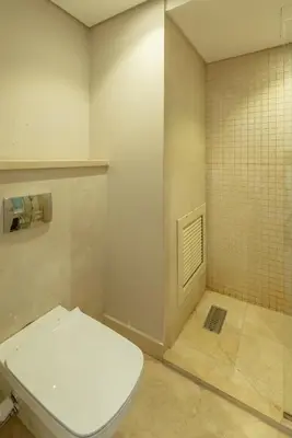 a bathroom with a toilet and a tiled wall at Fresh & Modern 1BR in El Gouna. Mangroovy Pool & Beach in Hurghada