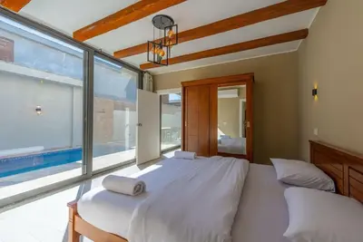 a large white bed in a bedroom with a large window at Modern & Comfy 2BR in Bali, El Gouna. Private Patio & Pool in Hurghada