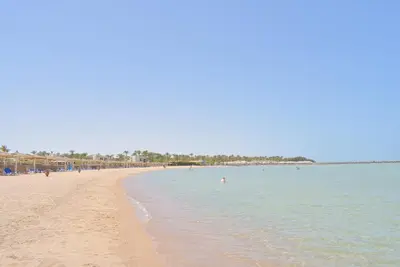 a beach with people swimming in the water at Jasmine Palace Resort in Hurghada