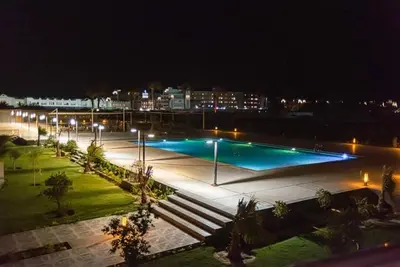 a large swimming pool at night with lights at Scandic resort 547 in Hurghada