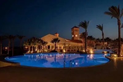 a large swimming pool in front of a building at night at veranda sahl hasheesh in Hurghada