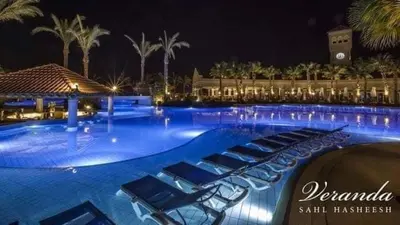 a large swimming pool with lounge chairs at night at veranda sahl hasheesh in Hurghada