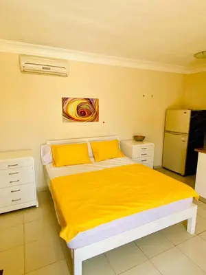 a bedroom with a bed with yellow sheets and a refrigerator at Hurghada-Magawish Studio 2 in Hurghada