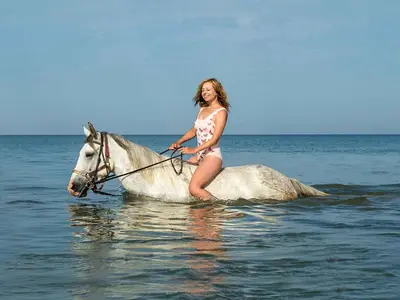 a woman in a bikini riding a horse in the water at Sunshine villa ( south Safaga ) in Safaga