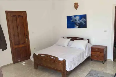 a bedroom with a bed with a wooden bed frame and a nightstand at Sunshine villa ( south Safaga ) in Safaga