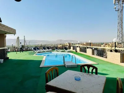 a pool on the roof of a building with a table and chairs at Queens Valley Hotel in Luxor