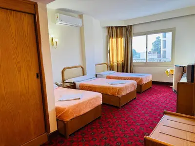 a hotel room with two beds and a television at Queens Valley Hotel in Luxor