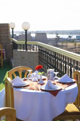 a table with plates and napkins on a balcony at Queens Valley Hotel in Luxor