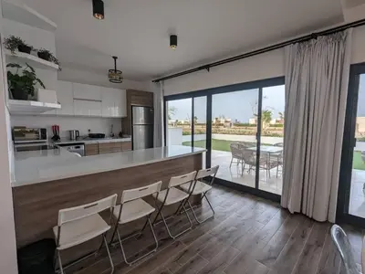 a kitchen with a counter with chairs and a table at Somabay Retreat 2BR Apartment in Hurghada