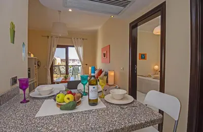 a table with a bowl of fruit and wine bottles at Buki-Gravity-Homes, Ap No2, seaview , HEATED pool, 5 star resort Gravity Sahl Hasheesh-FOR GUESTS WITH NONEGYPTIAN PASSPORTS in Hurghada