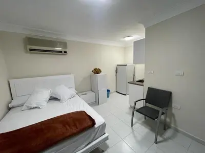 a white bedroom with a bed and a chair at One room in a compound with the swimming pool in Hurghada