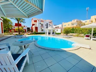 a swimming pool in a resort with chairs and an umbrella at One room in a compound with the swimming pool in Hurghada