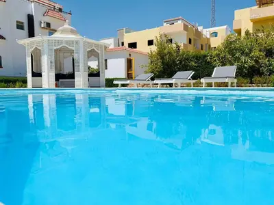 a swimming pool with a gazebo and blue water at One room in a compound with the swimming pool in Hurghada