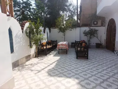 a courtyard with chairs and a table on a tile floor at West Bank Guest House in Luxor