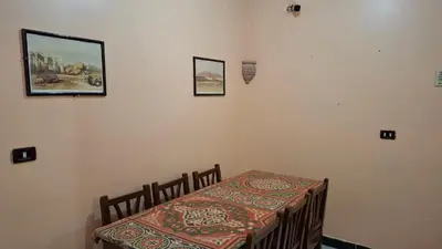 a dining room with a table and a bed with a table at West Bank Guest House in Luxor