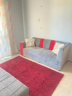 a couch in a living room with a red rug at Red Ruby Compound منتجع الياقوتة الحمراء in Hurghada