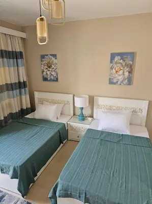 a room with two beds and a table with a lamp at Mangroovy- 1BR Bleu Ciel in Hurghada