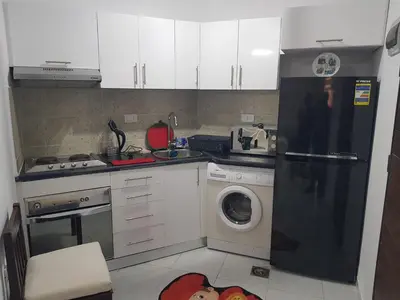 a kitchen with a black refrigerator and a washing machine at استديو هادي بوسط المدينه in Hurghada