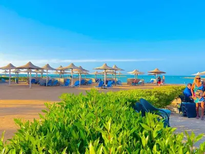 a beach with umbrellas and chairs and the ocean at Turtles Beach resort Hurghada Studio view sea view pool private beach Pools anf sunny balcony in Hurghada