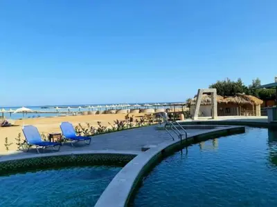 a swimming pool with two blue chairs and a beach at Turtles Beach resort Hurghada Studio view sea view pool private beach Pools anf sunny balcony in Hurghada