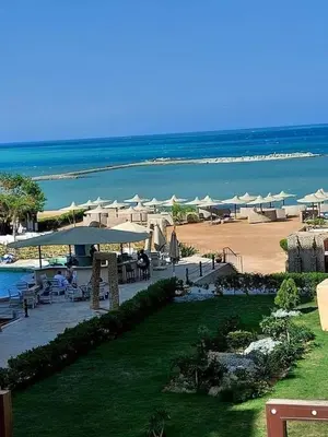 a beach with tables and umbrellas and the ocean at Turtles Beach resort Hurghada Studio view sea view pool private beach Pools anf sunny balcony in Hurghada