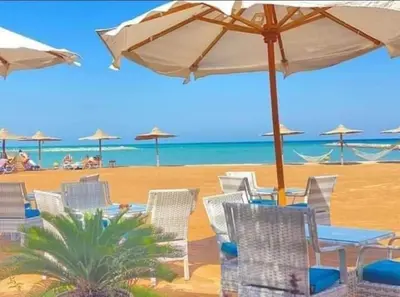 a group of chairs and tables with an umbrella on a beach at Turtles Beach resort Hurghada Studio view sea view pool private beach Pools anf sunny balcony in Hurghada
