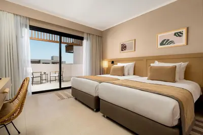 a hotel room with two beds and a balcony at JAZ Elite Amara in Marsa Alam City