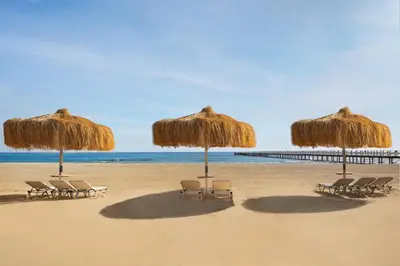 a group of chairs and umbrellas on a beach at JAZ Elite Amara in Marsa Alam City