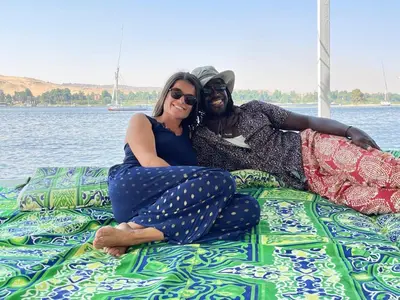 a man and a woman sitting on a blanket on a boat at Felucca sailing overnight experience with imaginative felucca aswan in Aswan