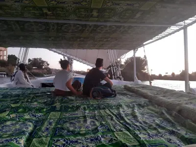 three people sitting on the floor of a boat at Felucca sailing overnight experience with imaginative felucca aswan in Aswan