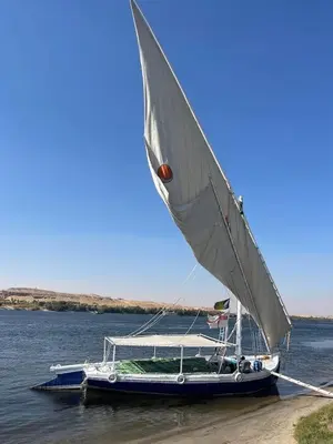 a boat with a sail sitting on the water at Felucca sailing overnight experience with imaginative felucca aswan in Aswan