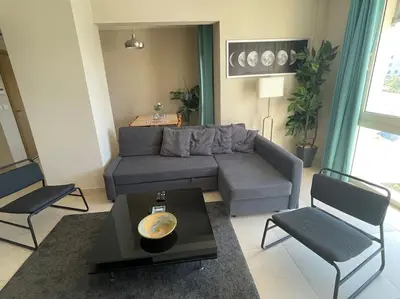 a living room with a couch and a table and chairs at Mangroovy- Sensational 1BR Sea & Kite view in Hurghada