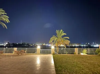 a patio with a palm tree at night at Royal Nile Villa - Luxury Nile View Apartment 1 in Luxor