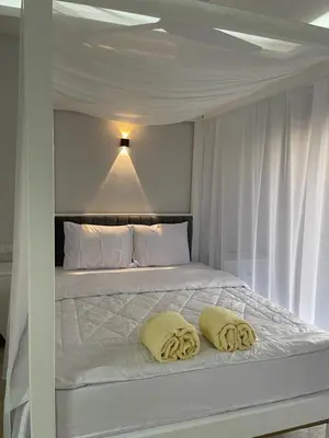 a white bed with two yellow pillows on it at Royal Nile Villa - Luxury Nile View Apartment 1 in Luxor